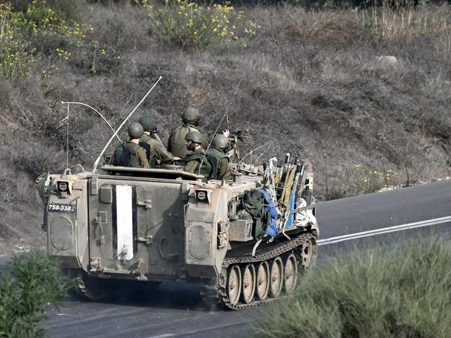 Israeli soldiers ride an armoured vehicle along a road on the outskirts of the southern Israeli city of Sderot on October 28, 2023, amid the ongoing war between Israel and the Palestinian group Hamas. Battles raged in Gaza on October 28, 2023, as Israel's army said it expanded ground operations after intensifying its bombardment of the Palestinian territory three weeks after the deadliest attack in the country's history. (Photo by Aris MESSINIS / AFP)