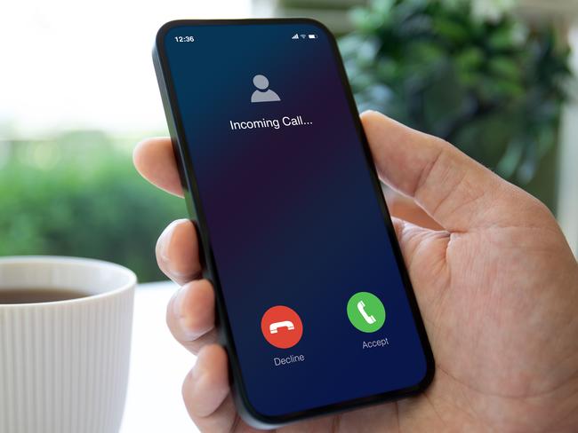 man hand holding phone with incoming call on screen in a cafe