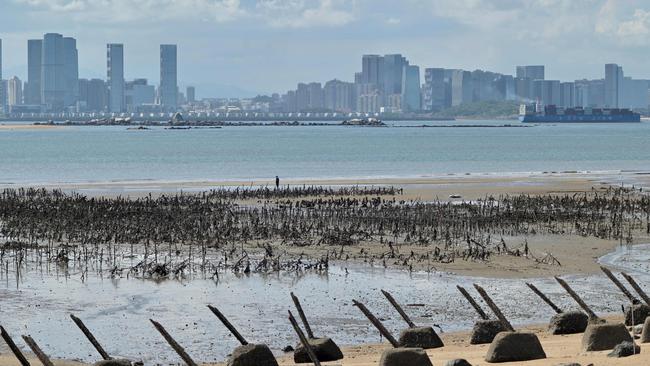 The Xiamen city skyline on the Chinese mainland is seen past anti-landing spikes placed along the coast of Lieyu islet on Taiwan's Kinmen islands. But China isn’t an unguided military threat. Picture: AFP.