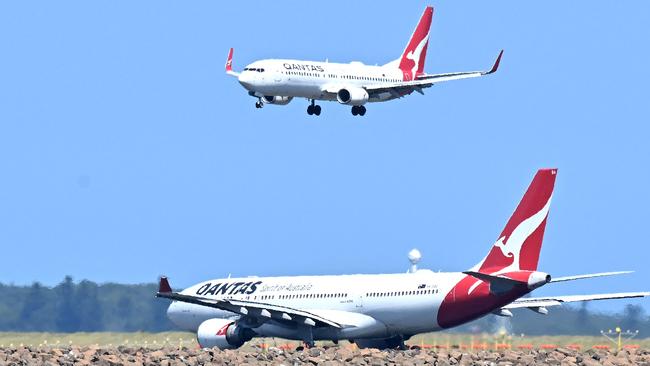 A Qantas plane (top) prepares to land at the Sydney International Airport on February 27, 2025. Australian airline Qantas said Thursday profits are up and demand for flights looks strong but it is still trying to win back trust after a string of scandals. (Photo by Saeed KHAN / AFP)