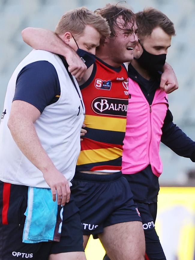 Injured Crow Luke Pedlar is helped from Adelaide Oval after injuring his ankle in the SANFL Showdown against Port Adelaide. Picture: SANFL Image/David Mariuz.