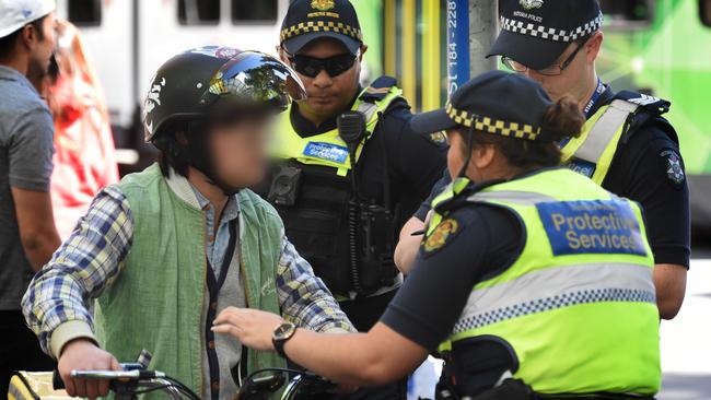 Three officers surround a rider. Picture: Tony Gough