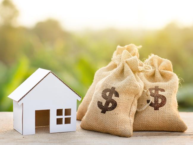 Loan and House concept. Money bags put near house on woodle desk at sunset and green nature background