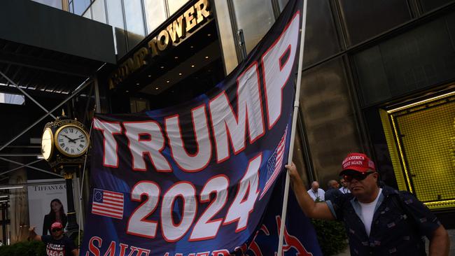 People hold a banner reading "Trump 2024" outside of the Trump Tower building in New York City after the former president’s home was raided. Picture: AFP