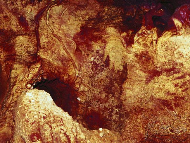 This colour enhanced image shows three hand stencils in the Maltravieso Cave in Spain. One has been dated to at least 66,000 years ago. Picture: Collado Giraldo