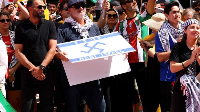 A protester pictured holding a flag that has a Nazi like symbol on it. Picture: NewsWire / Damian Shaw