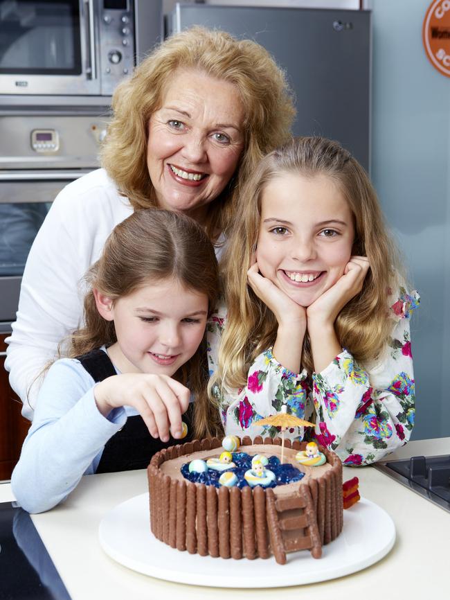 Pamela Clark, food director of the Australian Women's Weekly Test Kitchen, and her granddaughters Elspeth and Isobel pose with the iconic swimming pool cake in 2011.