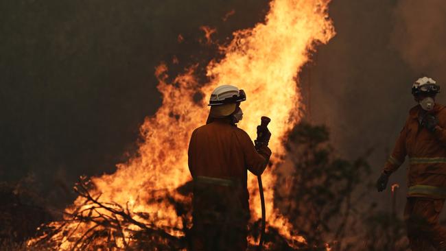 Tasmania Fire Service personnel put out a spot fire threatening a home on Donnelleys Rd, Geeveston, today. Picture: LUKE BOWDEN