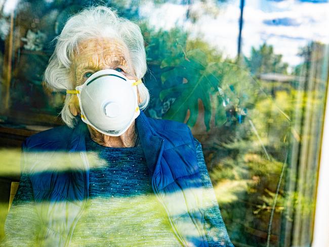 Distraught Elderly Senior Caucasian Woman Looking Out the Window Feeling Loneliness Wearing an n95 Protective Face Mask To Prevent the Spread of Covid. aged care generic