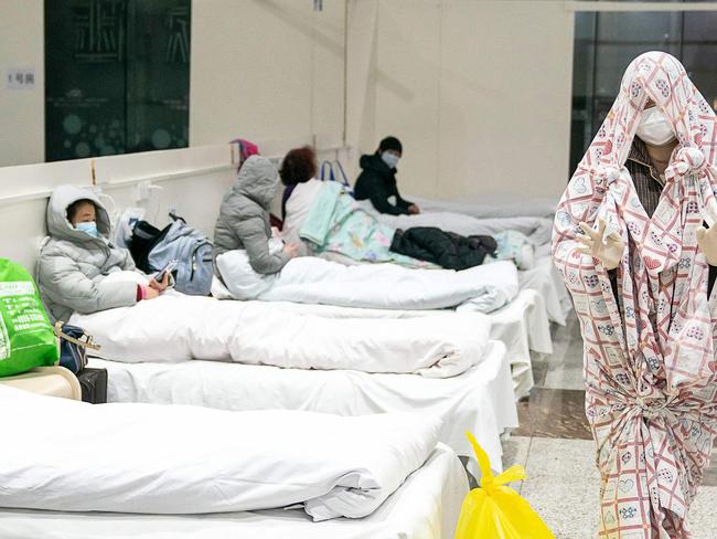 A patient (R) covered with a bed sheet at an exhibition centre converted into a hospital as it starts to accept patients displaying mild symptoms of the novel coronavirus in Wuhan in China's central Hubei province. Picture: AFP