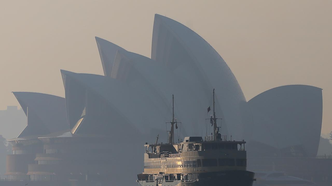 A ferry sails past the Sydney Opera House and the Sydney Harbour Bridge as winds blow smoke over the CBD in Sydney. Picture: AAP/Steven Saphore