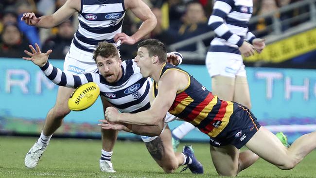 Crows Josh Jenkins gets his handpass out from Geelong’s Zach Tuohy. Picture SARAH REED