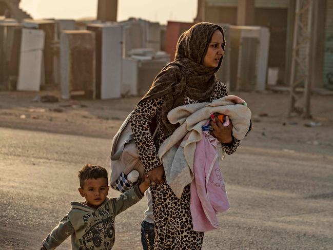 TOPSHOT - A woman flees with her children amid Turkish bombardment on Syria's northeastern town of Ras al-Ain in the Hasakeh province along the Turkish border on October 9, 2019. - Turkey launched a broad assault on Kurdish-controlled areas in northeastern Syria today, with intensive bombardment paving the way for an invasion made possible by the withdrawal of US troops. (Photo by Delil SOULEIMAN / AFP)