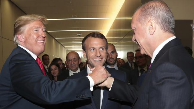 Donald Trump shakes hands with Turkey's Recep Tayyip Erdogan as France’s Emmanuel Macron looks on at the NATO summit in Brussels. Picture: AP