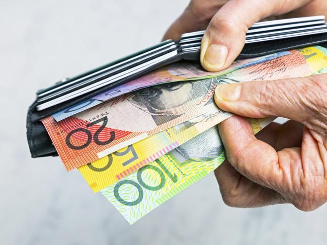 Close-up, senior female hands taking Australian banknotes (cash, currency) from purse containing many credit cards.  Horizontal, studio, copy space. Money generic