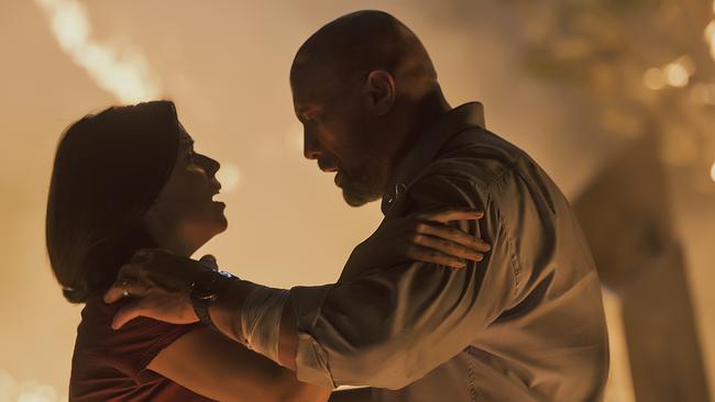 This image released by Universal Pictures shows Neve Campbell, left, and Dwayne Johnson in a scene from "Skyscraper." (Kimberley French/Universal Pictures via AP)