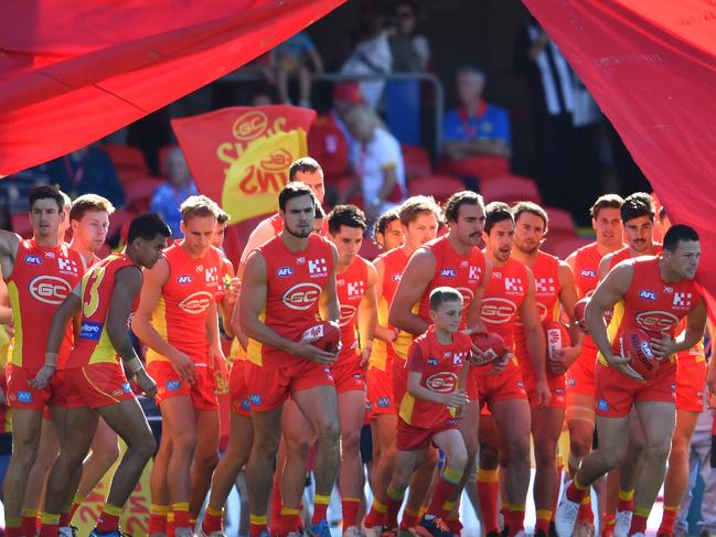 Suns players run through the banner before the Round 21 AFL match between the Gold Coast Suns and the Richmond Tigers at Metricon Stadium. Picture: AAP Image/Darren England.