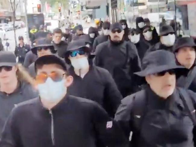 Members of the National Socialist Network march through the Brisbane CBD surrounded by police.