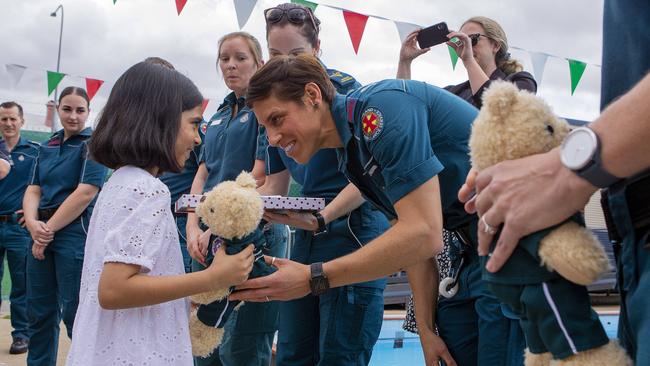 Leenah Ali, 7, with the QAS crews that helped her life and talking to advanced paramedic Celeste Trembath. Picture: Jerad Williams