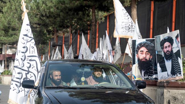 Supporters drive past Taliban flags along a road in Kabul.