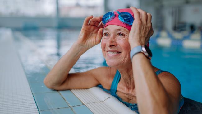 A happy senior woman in swimming pool, leaning on edge. Active retirement generic.