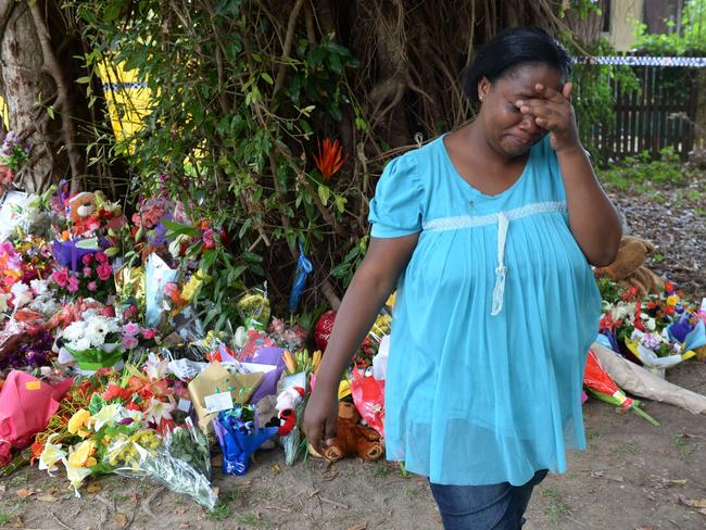 A woman cries after laying flowers at the scene where eight children were found dead.