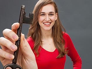 relaxed beautiful woman holding big key as symbol of success