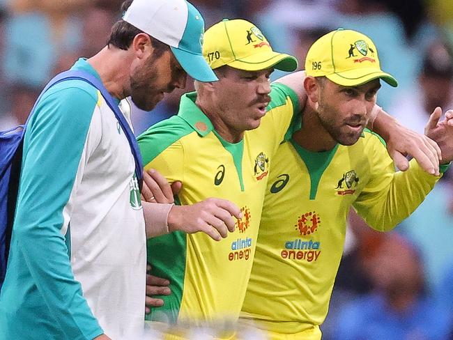 (FILES) This file photo taken on November 29, 2020 shows Australia's David Warner (C) being assisted by teammate Glenn Maxwell (R) and a trainer as he leaves the field after he suffered an injury during the one-day cricket match against India at the Sydney Cricket Ground (SCG) in Sydney. - Star Australian batsman David Warner will miss the Boxing Day Test against India after failing to shake off the groin injury that kept him out of the opening fixture, Cricket Australia said on December 23, 2020. (Photo by DAVID GRAY / AFP) / -- IMAGE RESTRICTED TO EDITORIAL USE - STRICTLY NO COMMERCIAL USE --