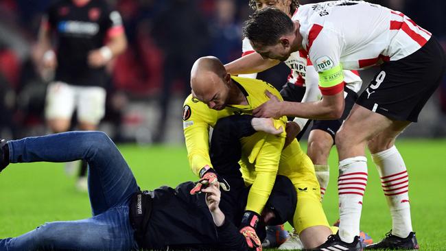 A pitch invader is on the ground after attempting an assault on Sevilla FC goalkeeper Marko Dmitrovic (C) during the UEFA Europa league play-off match between PSV Eindhoven and Sevilla FC at the Phillips stadium in Eindhoven on February 23, 2023. (Photo by Olaf Kraak / ANP / AFP) / Netherlands OUT