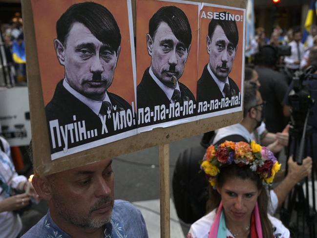 A man holds a sign depicting Russian President Vladimir Putin as Adolf Hitler during a protest by members of the Ukrainian community, outside of the Russian embassy in Buenos Aires on March 1, 2022. Picture: JUAN MABROMATA / AFP