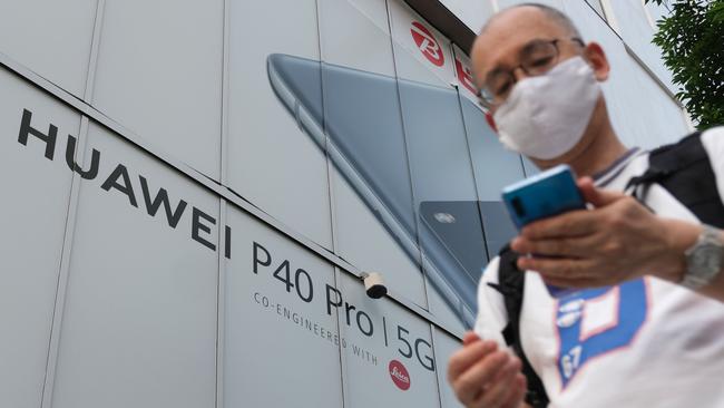 A pedestrian walks under an advertisement for Chinese telecoms company Huawei. Picture: AFP