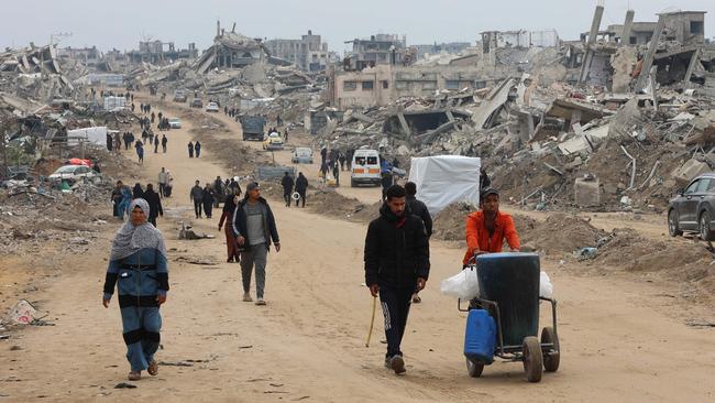 Palestinians walk past collapsed buildings in the northern Gaza Strip. Picture: AFP.