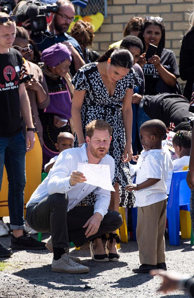 A boy offers a gift to Prince Harry in Cape Town. Picture: David Harrison/AFP.