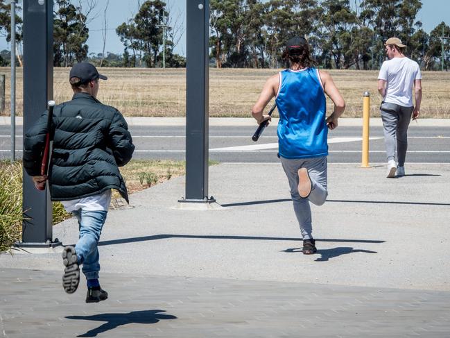 Youths involved in a standoff at Wyndham Vale station run with baseball bats. Picture: Jake Nowakowski