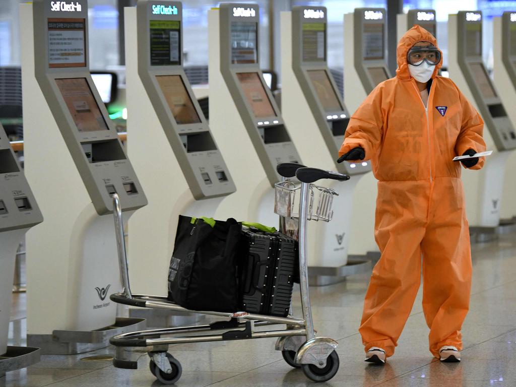 A passenger wearing protective clothing against the COVID-19 coronavirus uses a self check-in machine at Incheon international airport. Picture: Jung Yeon-je / AFP