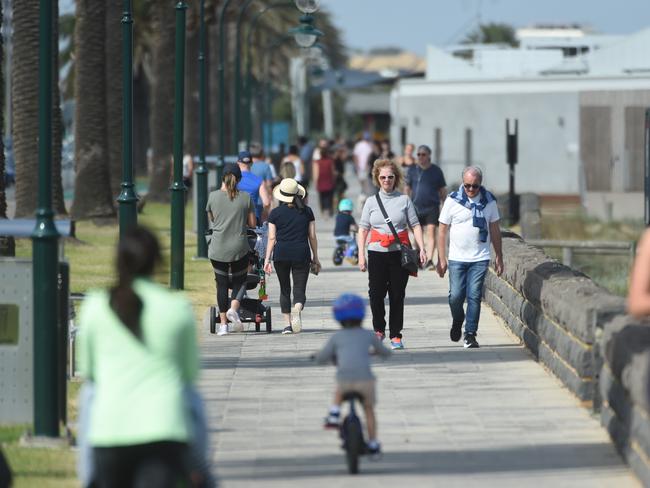 Locals walk along Port Melbourne beach. Picture: Tony Gough