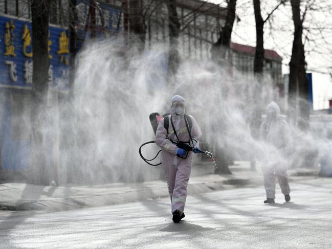 People in protective suits spraying disinfectant on a street in Shijiazhuang, in northern China's Hebei province. Picture: STR / CNS / AFP / China OUT
