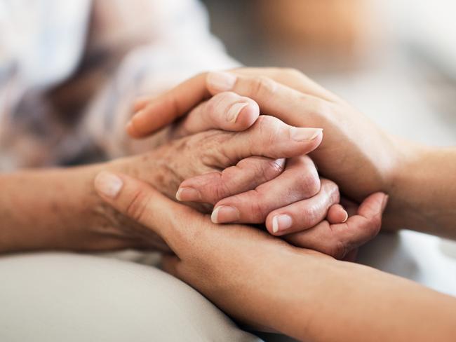 Cropped shot of an unidentifiable nurse consoling her elderly patient by holding her hands at home