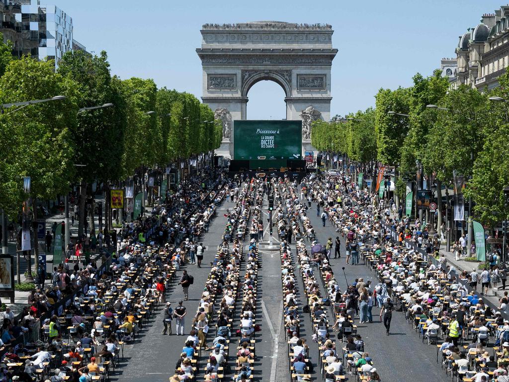 TOPSHOT - This photograph shows the prestigious Champs-Elysees Avenue, transformed into a giant classroom hosting participants, as they attempt to beat the record of the "World's Biggest Dictation" in Paris on June 4, 2023. (Photo by ALAIN JOCARD / AFP)