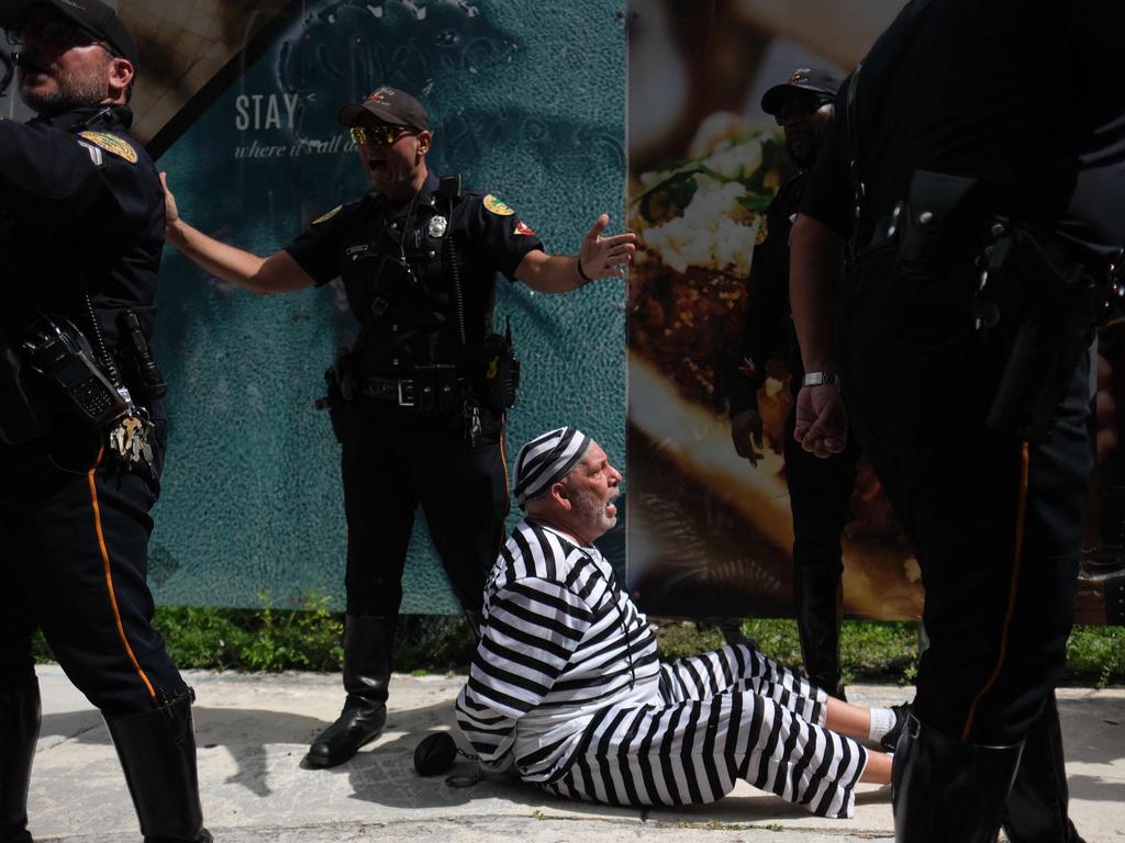 A protester surrounded by police after running in front of Trump’s motorcade. Picture: AFP