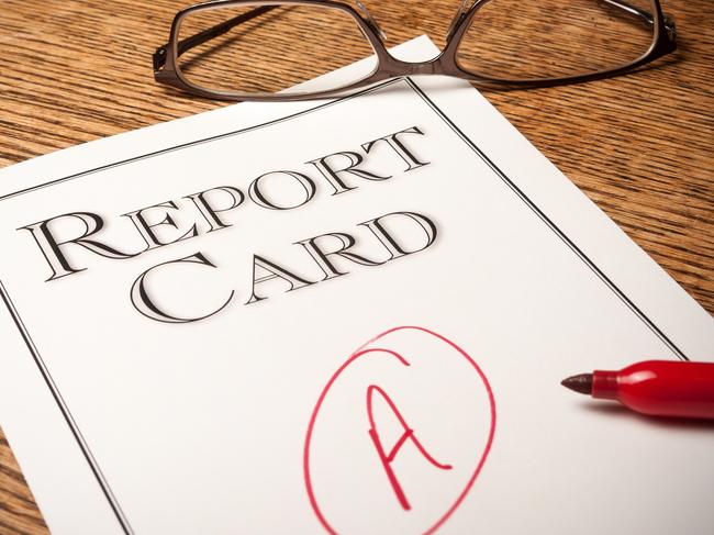 Report card on an oak desk with a red Ã¢â¬ÅAÃ¢â¬Â written on it . A red pen in the foreground and glasses in the background.