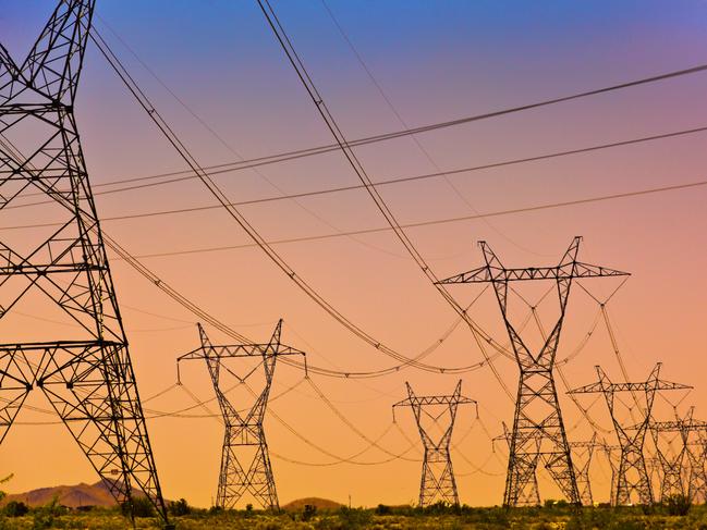 a Series of electrical transmission tower with power lines criss crossing at sunset.