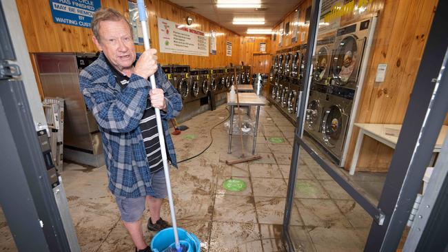 Lilydale laundromat owner Brian Hamilton cleans up after the flood wrecks his business. Picture: Tony Gough