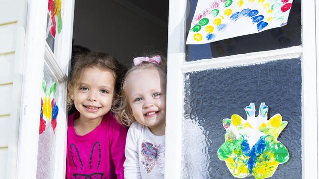 Sana Roe, 3 and sister Thea, 1 show off the colourful paintings on one of the windows of their Sandgate home. Picture: AAP/Renae Droop