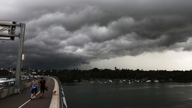 People walk across Iron Cove bridge, Drummoyne, in Sydney’s inner west, as storm clouds gather overhead at Iron Cove Bay. Storm cells passed over the city causing widespread flooding and damage.