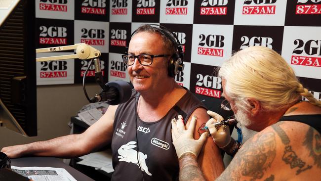 Souths supporter Chris Smith receives a tattoo of a Bunny from Tony Cohen on air during his 2GB radio show at Pyrmont. Picture Craig Greenhill