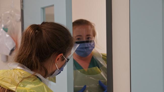 Hayley Austin, registered nurse, communicates to her colleague while working in the emergency department’s COVID-19 quarantine zone for new arrivals. Picture: Mark Isaacs