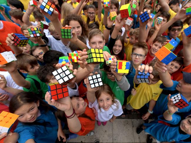 TOPSHOT - Hungarian pupils pose with Rubik's Cubes during a flashmob to celebrate the 50th anniversary of Hungarian architect Erno Rubikâs invention, in Budapest on June 12, 2024. In 1974, Hungarian architecture professor Erno Rubik created the first prototype of a movable cube made out of small wooden blocks and held together by a unique mechanism. More than 500 million copies of the cult object have been sold -- not counting the myriad of counterfeits. Rubik's Cube has remained one of the world's top-selling puzzle games, with more than 43 quintillion -- a quintillion being a billion trillion -- ways of solving it. (Photo by Ferenc ISZA / AFP)