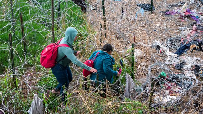 Immigrants pick their way through the razor wire after crossing the Rio Grande in Eagle Pass, Texas. Picture: AFP