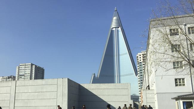 Residents pass by the towering Ryugyong Hotel in Pyongyang, North Korea. Thirty years after work began on what was then one of the tallest hotel projects ever attempted, the inside of the structure has yet to be completed and mystery swirls over whether it ever will ever open for guests. Photo: Eric Talmadge